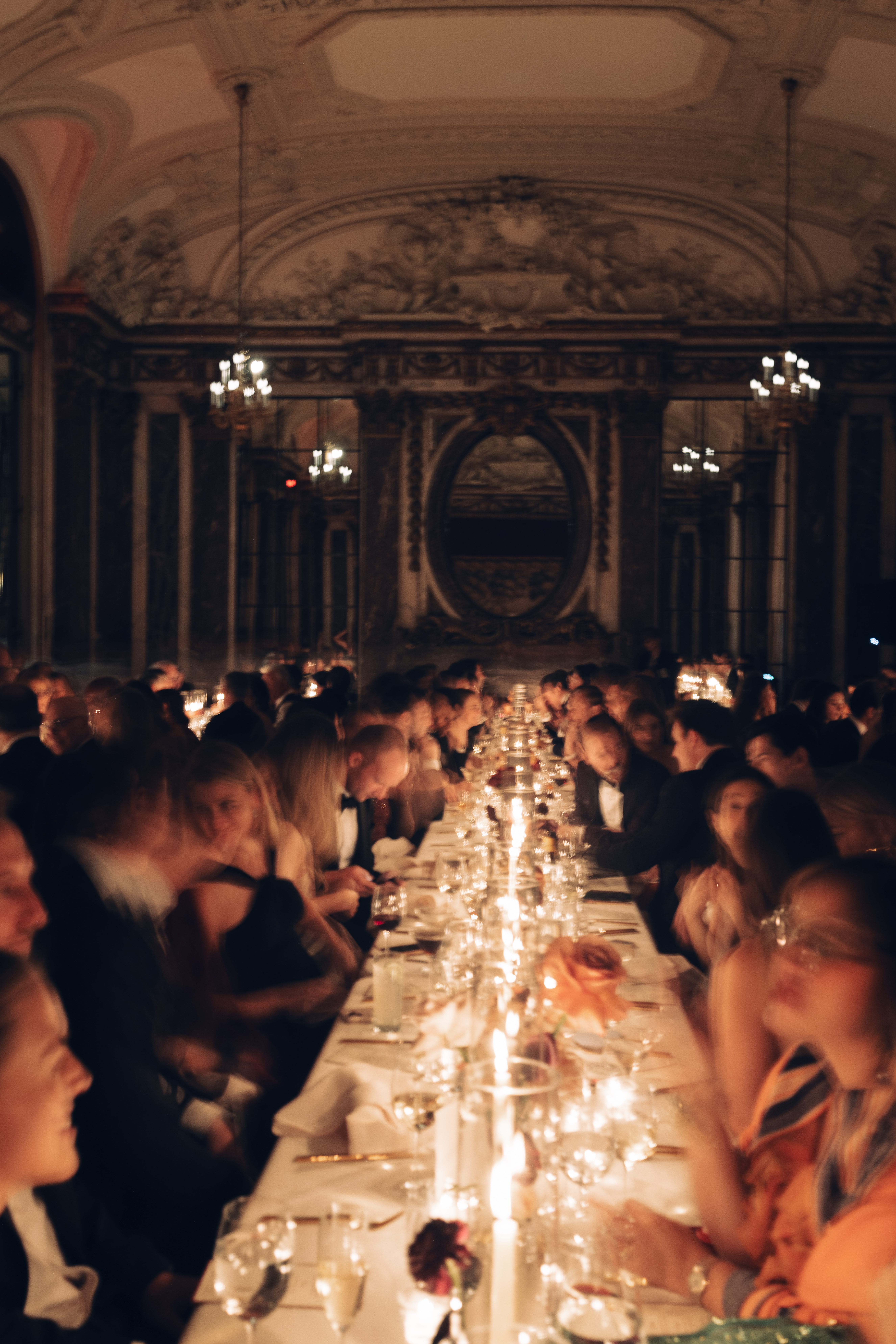 Guests seated at long tables in dim, romantic lighting