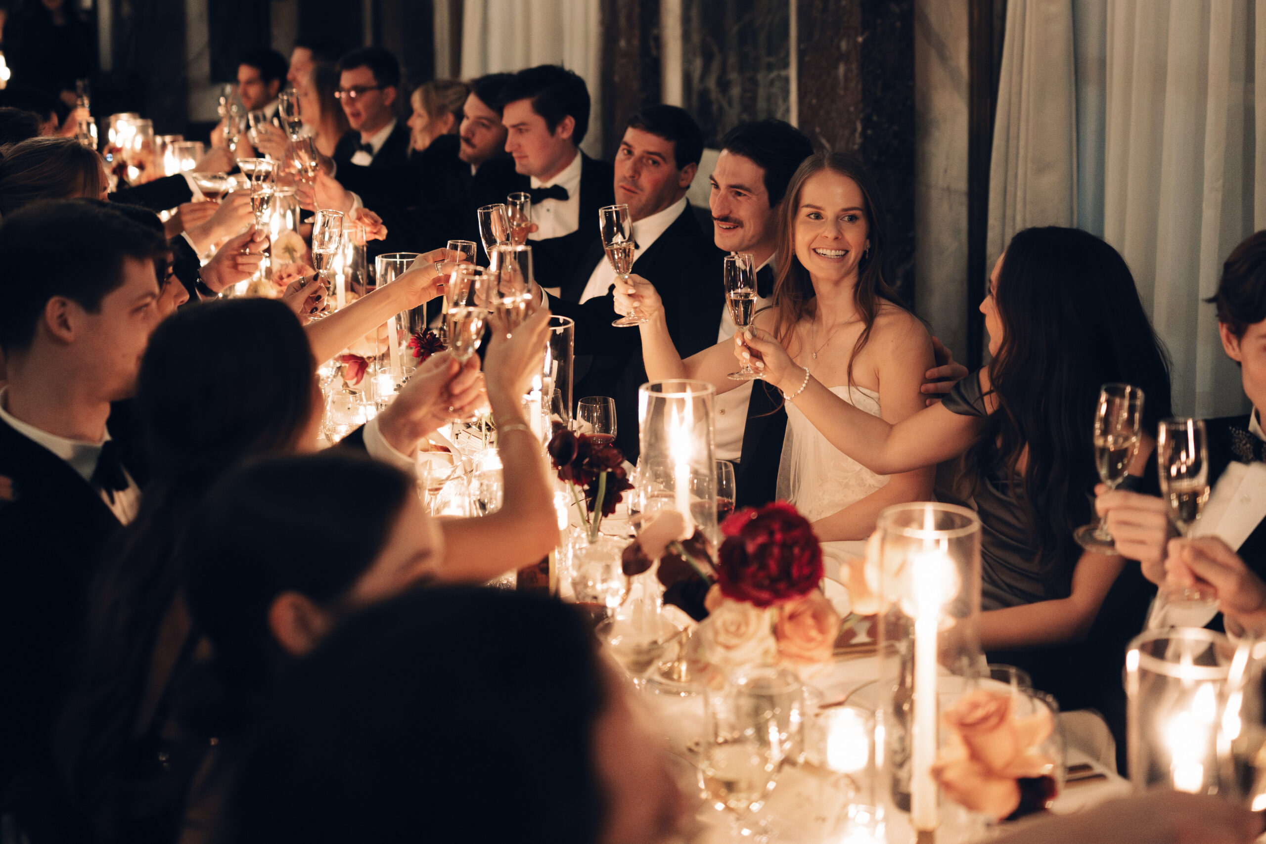 Guests seated at long tables in dim, romantic lighting