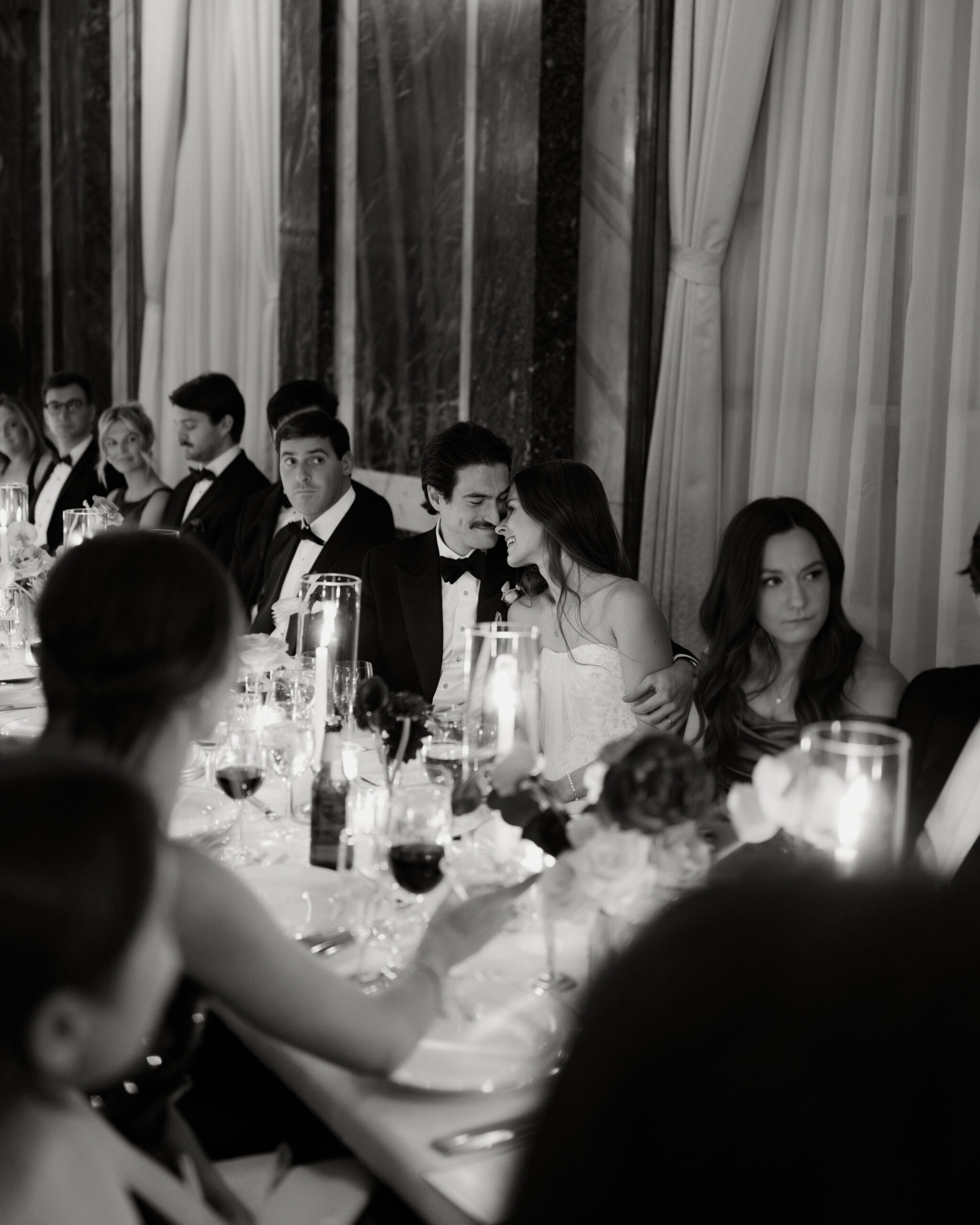Guests seated at long tables in dim, romantic lighting