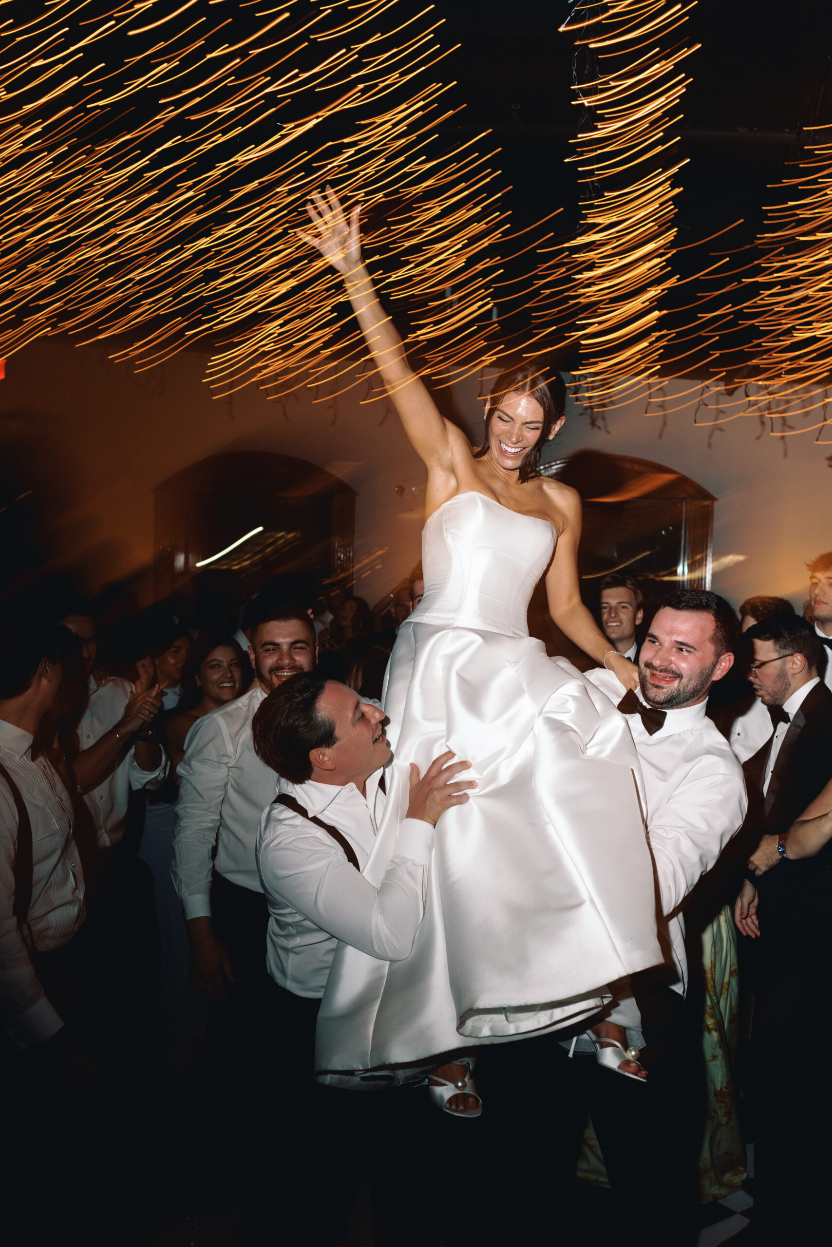 Dance floor moment with guests mid-spin under twinkle lights at the reception