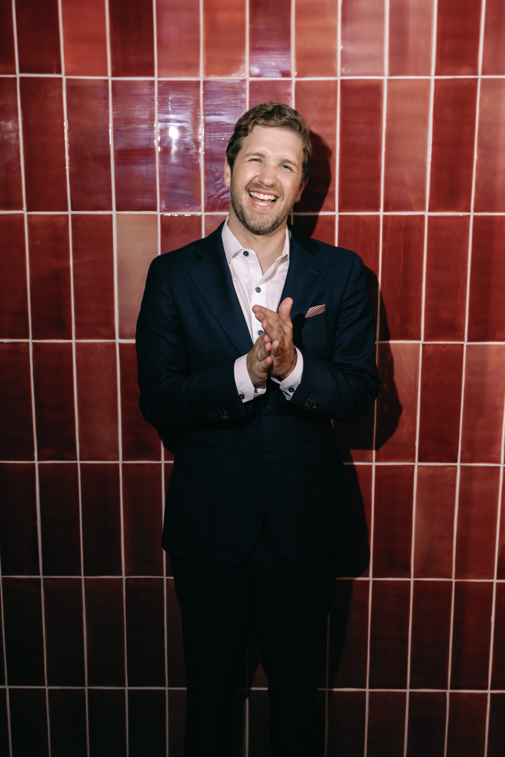 Groom in editorial moment in New York City portrait with red wall